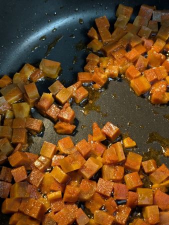 pot full of diced seitan bacon being sautéed in melted coconut oil