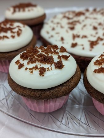 close-up of a vegan chocolate umami velvet cupcake with vegan cream cheese frosting topped with stray crumbs