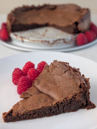 closeup of a single slice of vegan fallen chocolate souffle cake garnished with raspberries