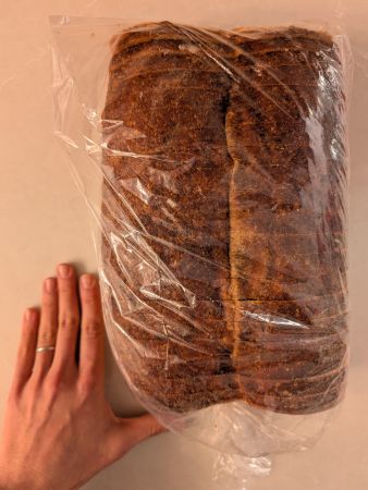 bagged loaf of Tomato Basil Bread from Panera next to average female adult hand for size reference