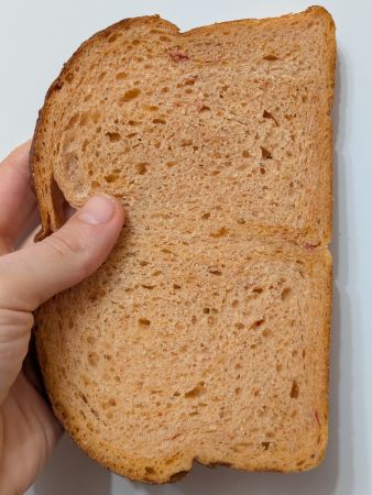 slice of Panera's Tomato Basil Bread held vertically showing structure and texture described in post